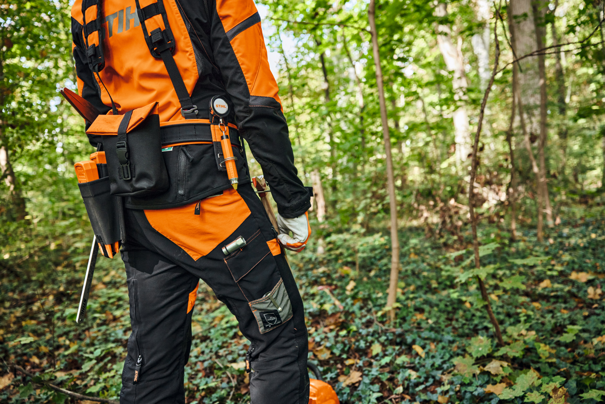 Una persona lleva un equipo de protección y el sistema de arnés modular STIHL ADVANCE X-Flex en el bosque